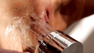 Wet blonde plays with showerhead then fingers herself on bed